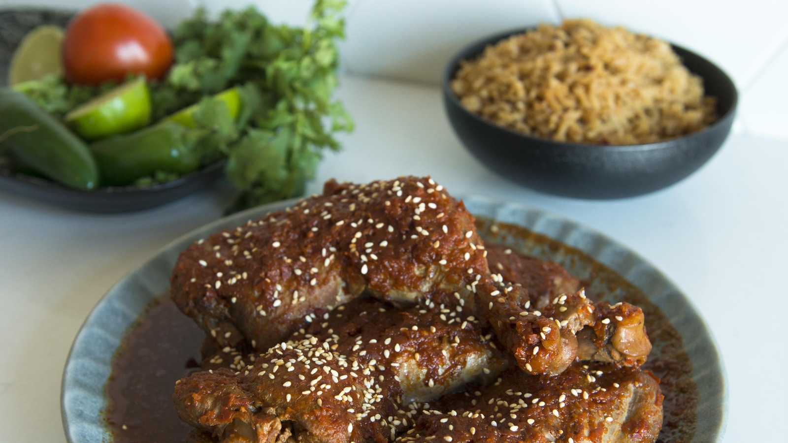 Un bol contient des pièces de poulet dans une sauce tomatée. Sur la table il y a aussi un bol de salade et un bol de riz. Un bol contient des pièces de poulet dans une sauce tomatée. Sur la table il y a aussi un bol de salade et un bol de riz.