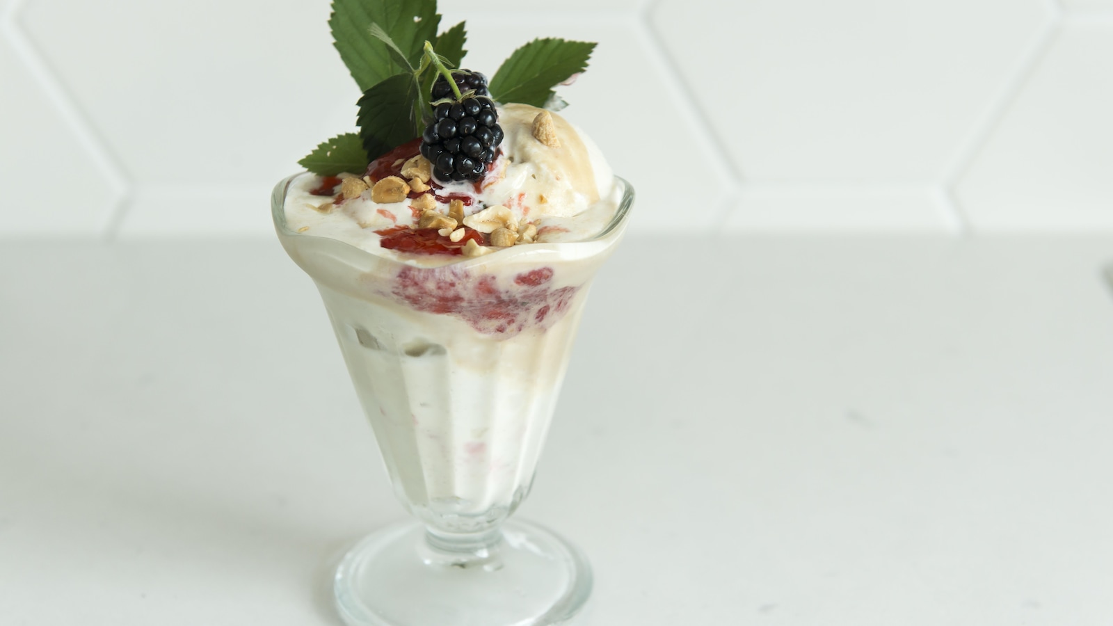 Un sundae dans une coupe de verre, garni de mûres et de verdure. Un sundae dans une coupe de verre, garni de mûres et de verdure.