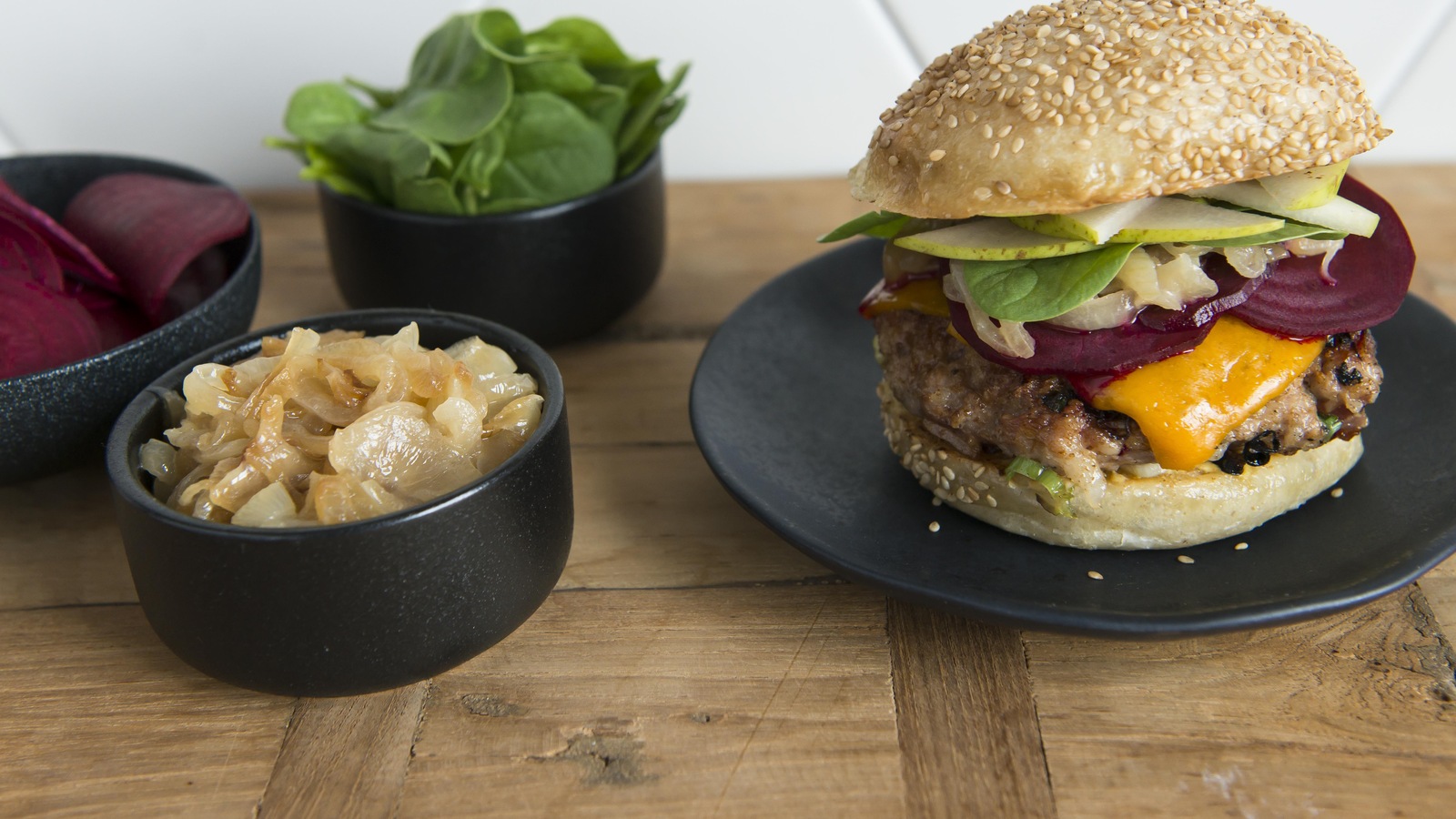 Un burger de porc avec bacon, oignons caramélisés et tranches de betteraves.
Un burger de porc avec bacon, oignons caramélisés et tranches de betteraves.