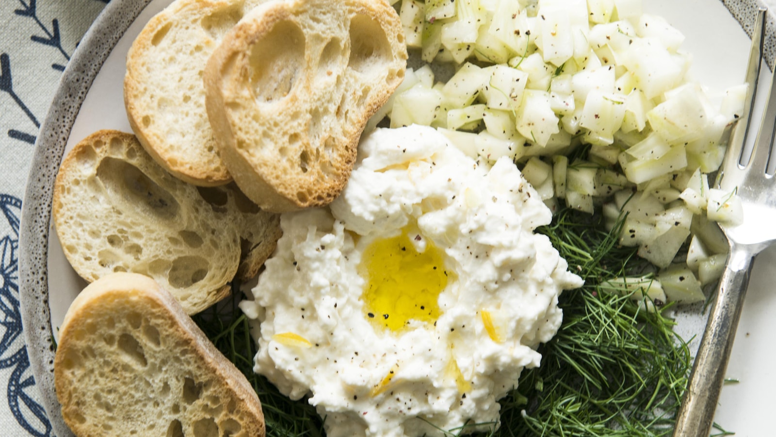 Une assiette de burrata au citron accompagné de croûton de pain de fenouil en dés. Une assiette de burrata au citron accompagné de croûton de pain de fenouil en dés.