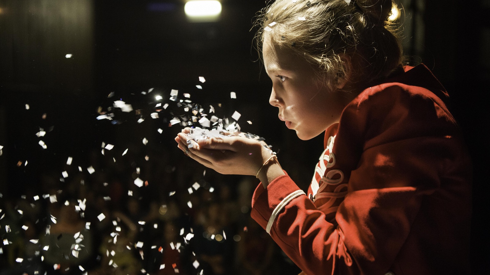 Une petite fille souffle sur un tas de confettis dans ses mains Une petite fille souffle sur un tas de confettis dans ses mains