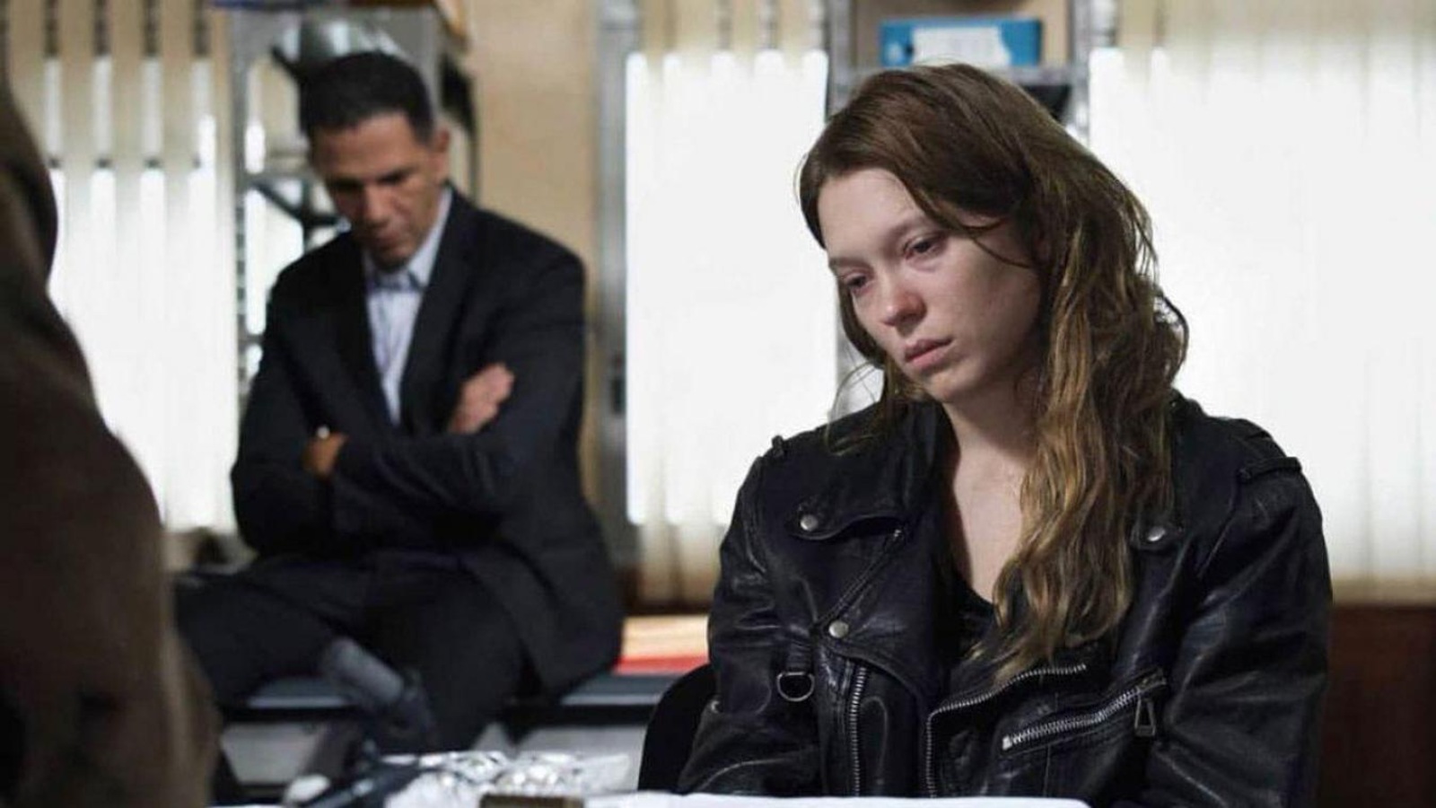 Une jeune femme au visage défait, en blouson de cuir, interrogée par la police. Une jeune femme au visage défait, en blouson de cuir, interrogée par la police.