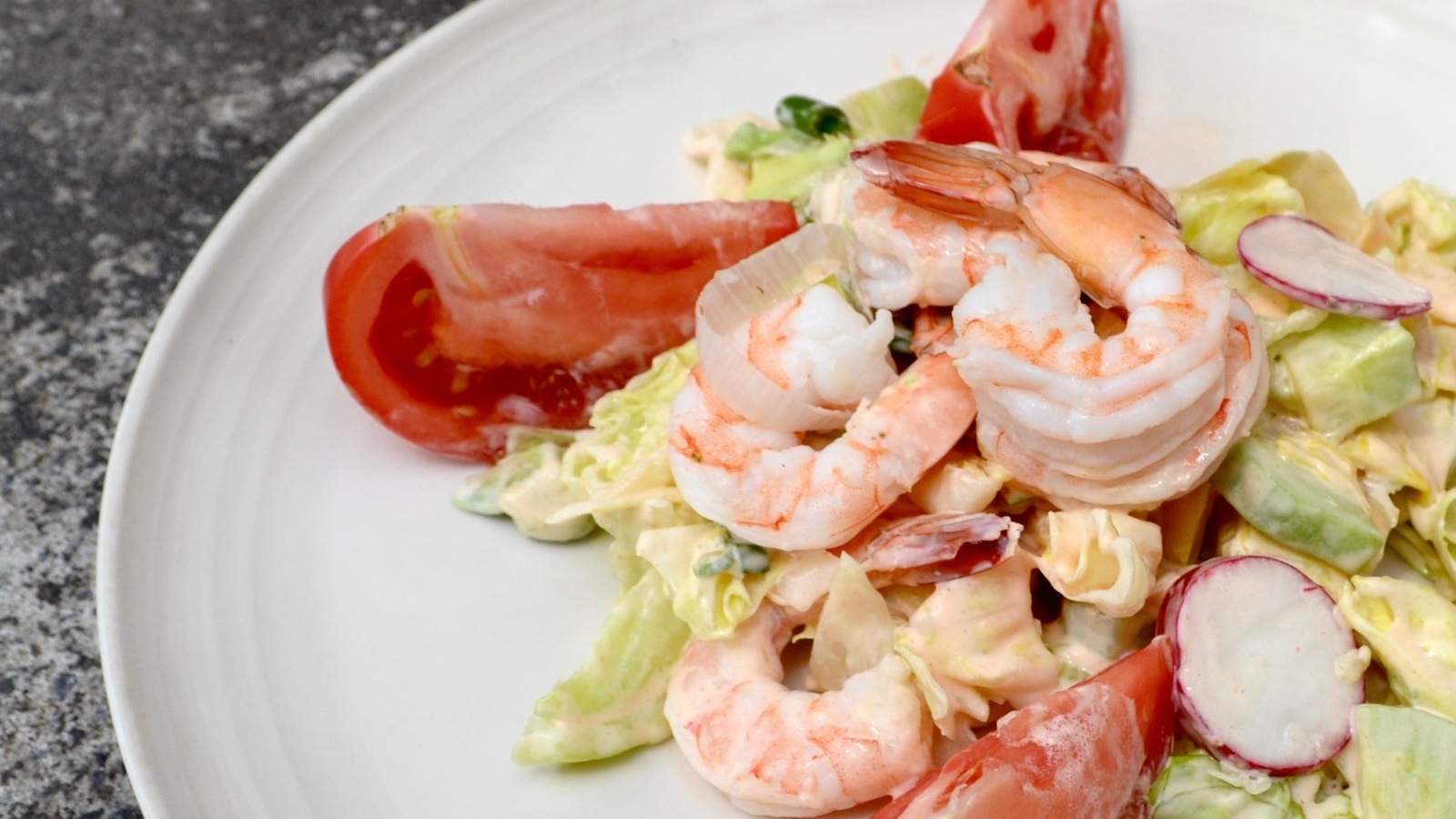 Salade estivale de crevettes présentée dans une assiette blanche Salade estivale de crevettes présentée dans une assiette blanche