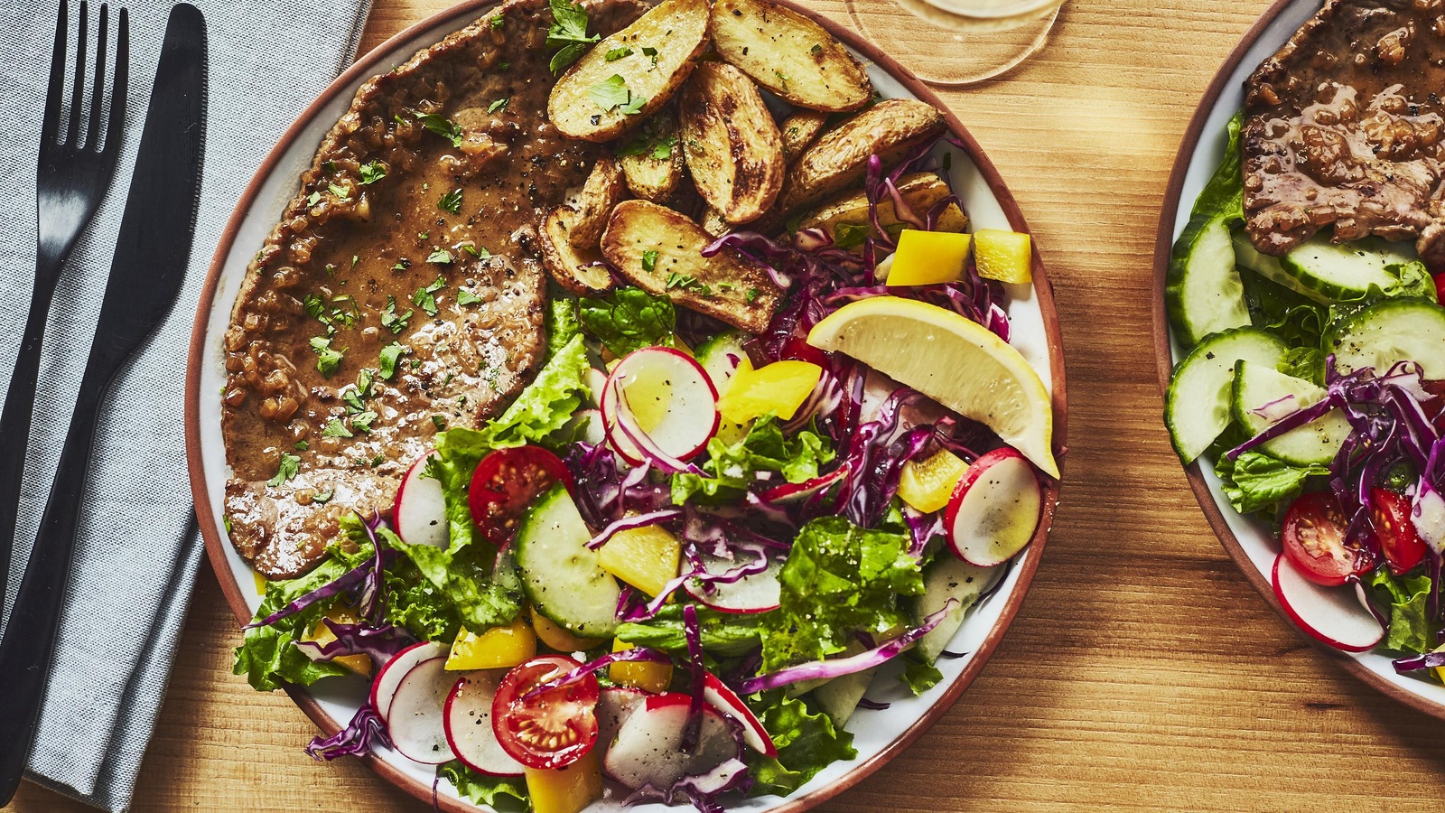 Une assiette d'escalope, accompagnée d'une salade et de patates, est sur la table. Une assiette d'escalope, accompagnée d'une salade et de patates, est sur la table.