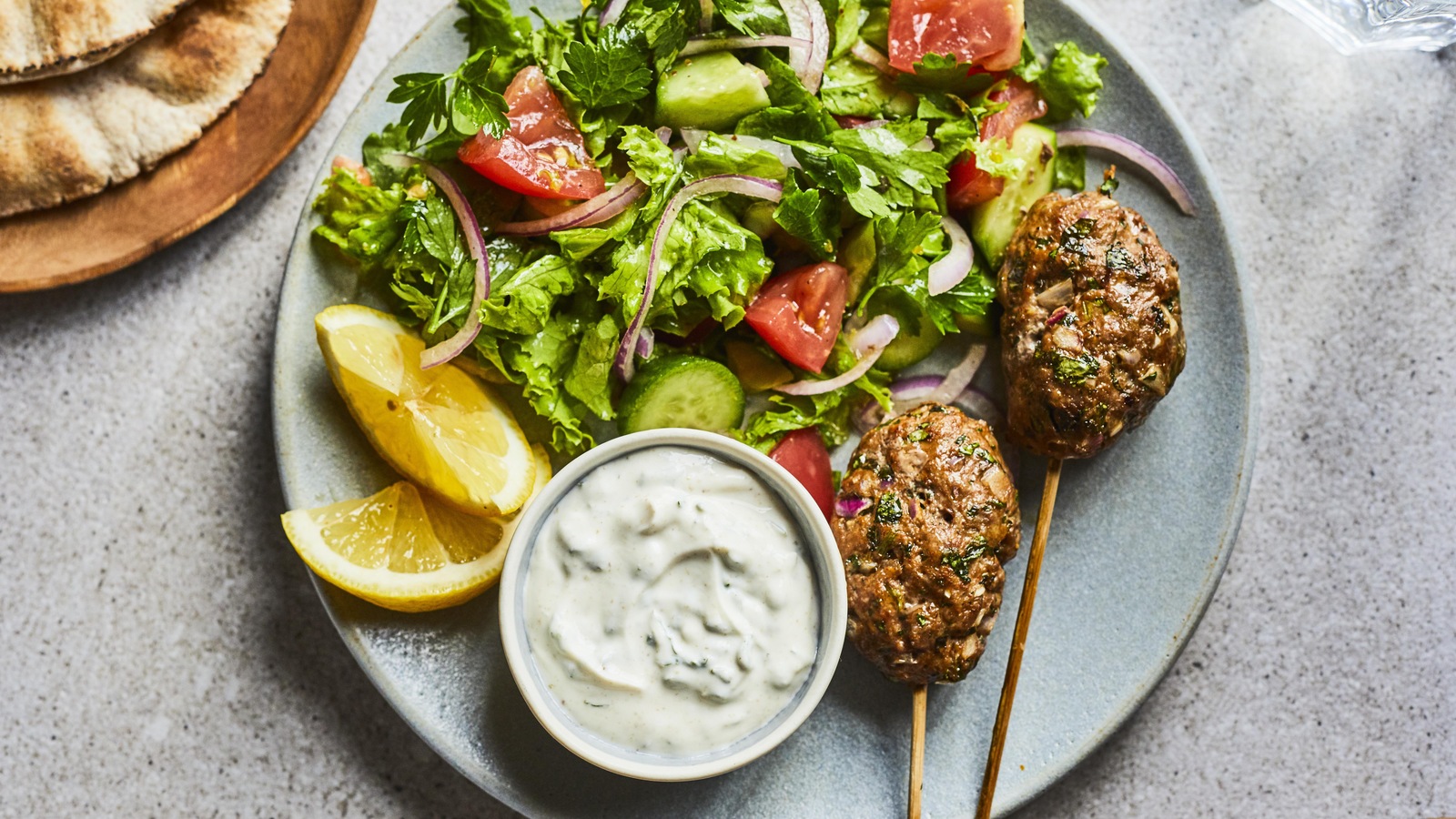 Les keftas sont dans une assiette accompagnés d'une salade et d'une sauce. Les keftas sont dans une assiette accompagnés d'une salade et d'une sauce.