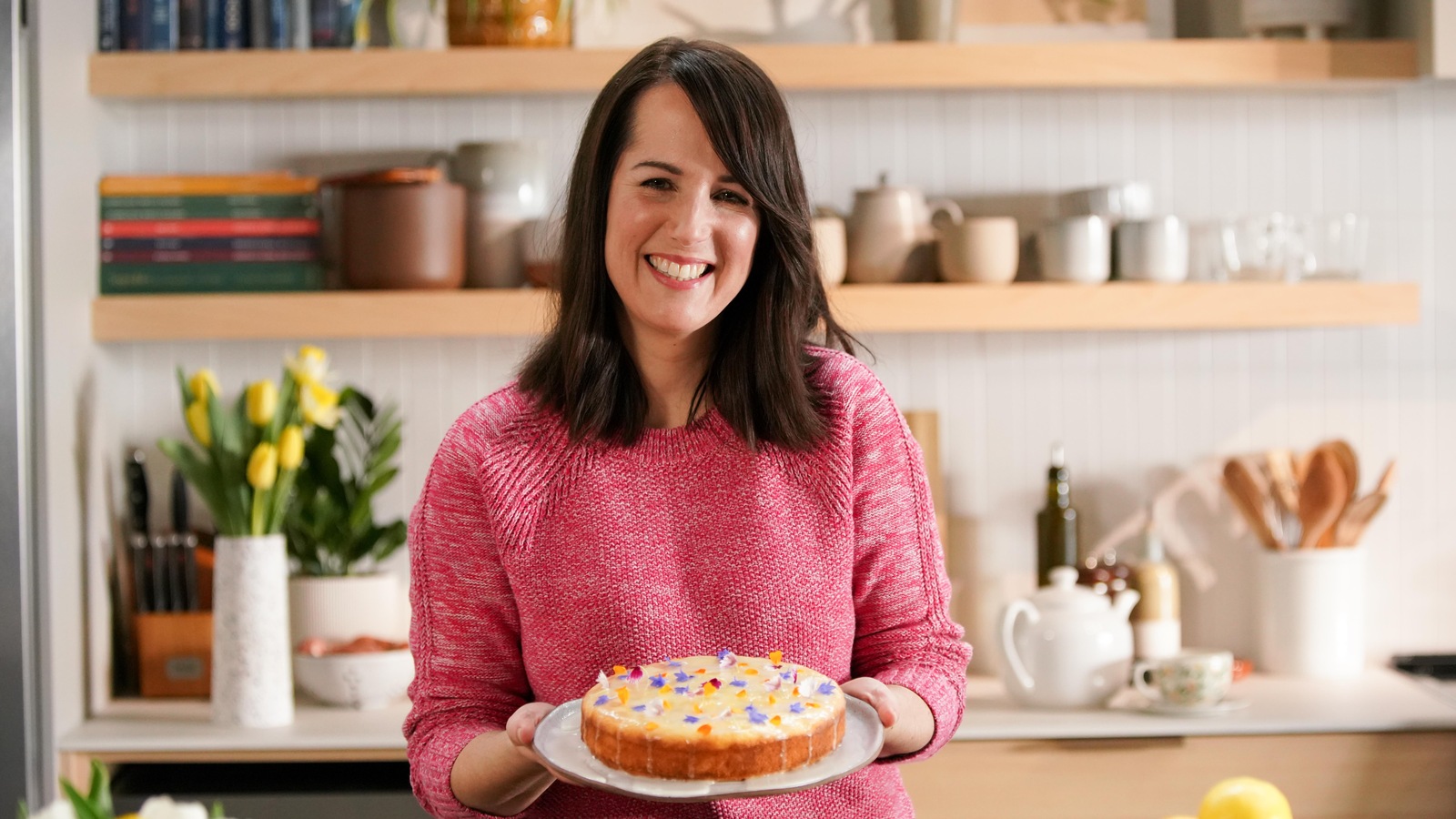 Geneviève O'Gleman tient un gâteau décoré avec des fleurs. Geneviève O'Gleman tient un gâteau décoré avec des fleurs.