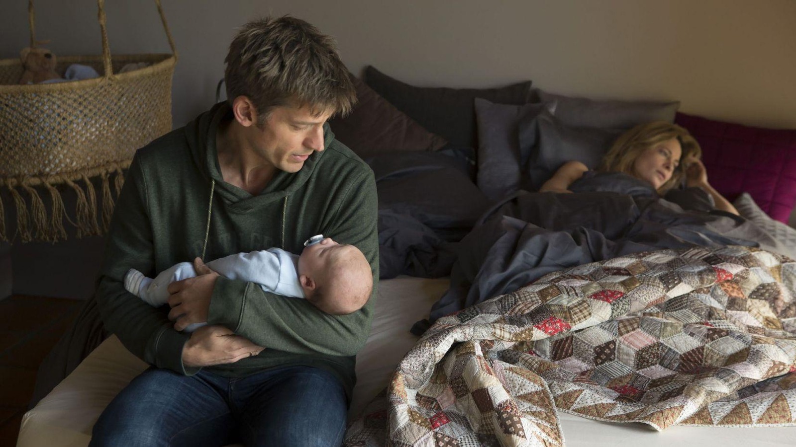 Une femme dans un lit, un homme assis sur le lit, un bébé dans les bras. Une femme dans un lit, un homme assis sur le lit, un bébé dans les bras.