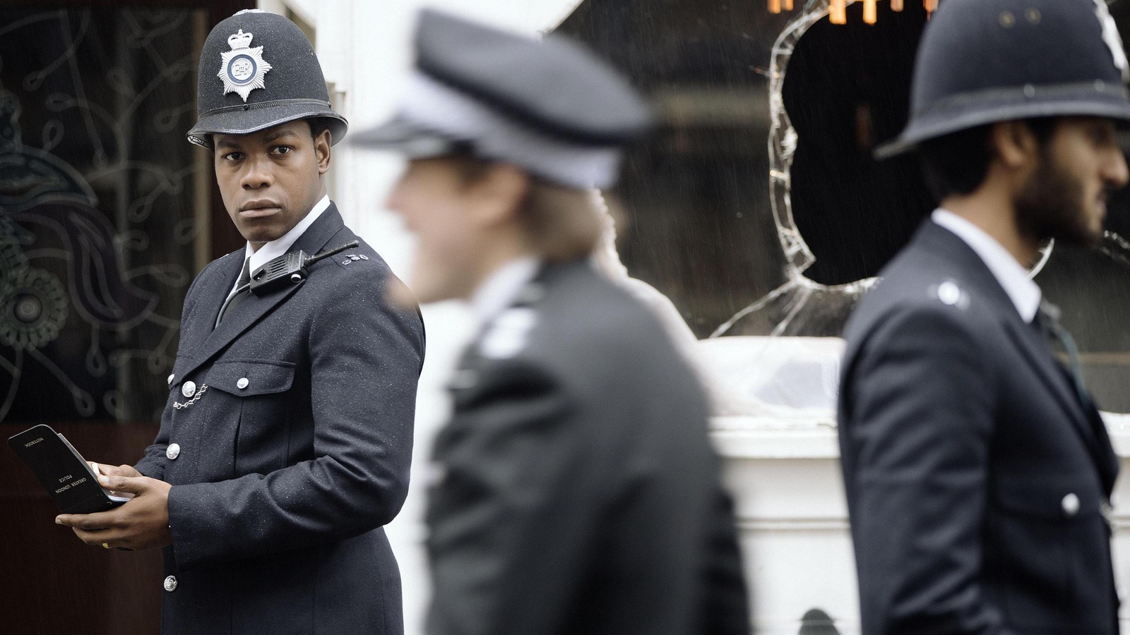 Un jeune homme (John Boyega) en tenue de policier britannique, dans la rue.
