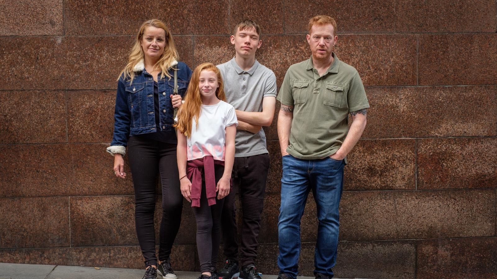 Une famille pose devant un mur en briques. Une famille pose devant un mur en briques.