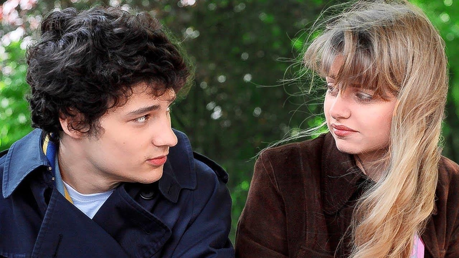 Un jeune homme et une jeune femme assis dehors se regardent. Un jeune homme et une jeune femme assis dehors se regardent.