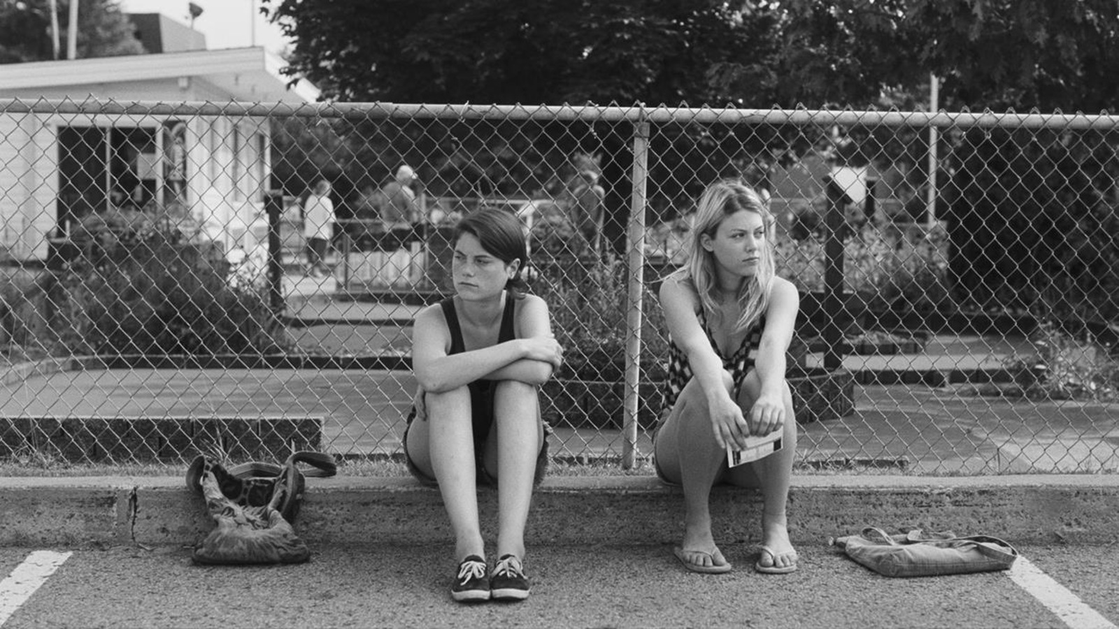 En noir et blanc, deux jeunes filles assises sur un rebord de trottoir En noir et blanc, deux jeunes filles assises sur un rebord de trottoir