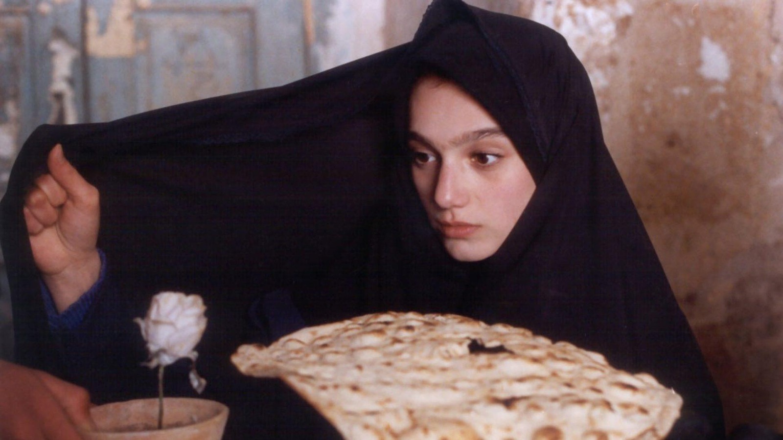 Une femme voilée tient un pain plat dans une main, de l'autre son voile, tandis qu'on lui tend un pot avec une fleur. Une femme voilée tient un pain plat dans une main, de l'autre son voile, tandis qu'on lui tend un pot avec une fleur.