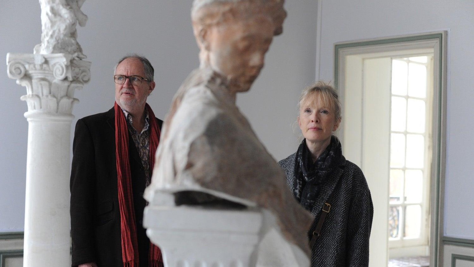 Un homme et une femme dans un musée, devant un buste en marbre.