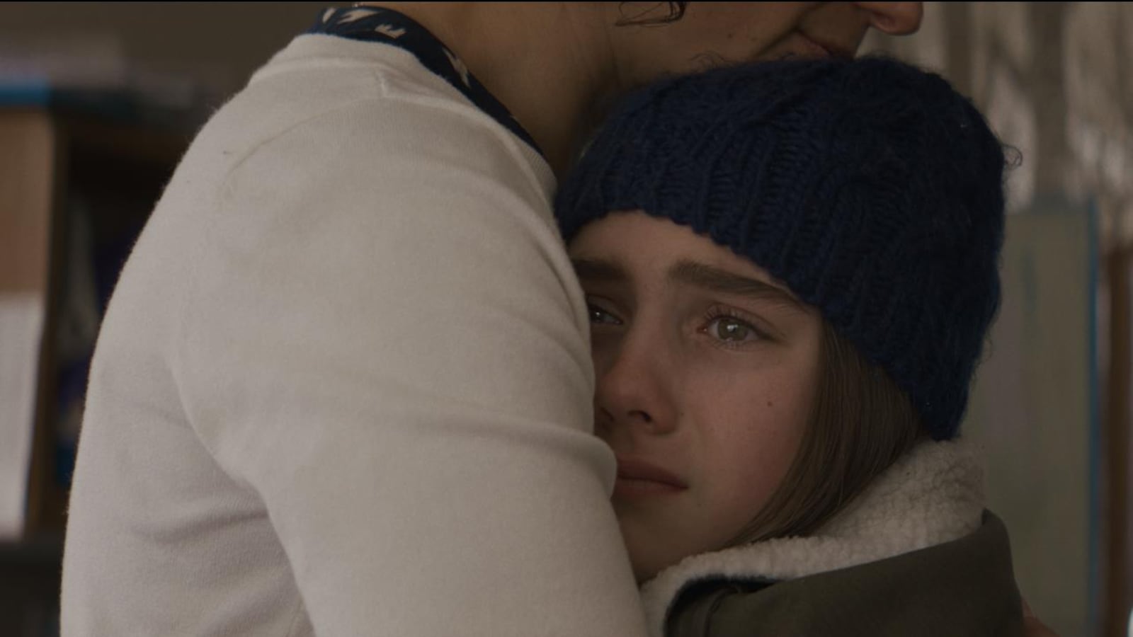 Une jeune fille portant un bonnet, les yeux pleins de larmes, collée contre une femme. Une jeune fille portant un bonnet, les yeux pleins de larmes, collée contre une femme.
