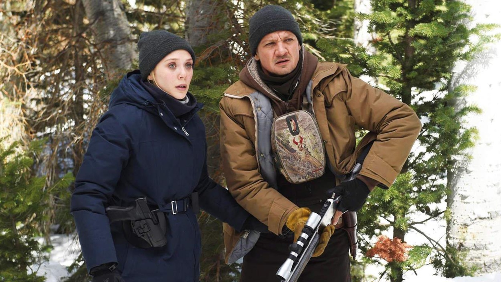 Une femme et un homme, armés, en tenues d'hiver, dans une forêt. Une femme et un homme, armés, en tenues d'hiver, dans une forêt.