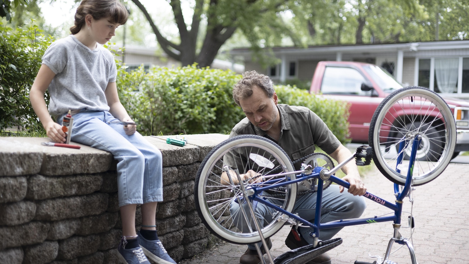 Élise regarde son père réparer son vélo.
