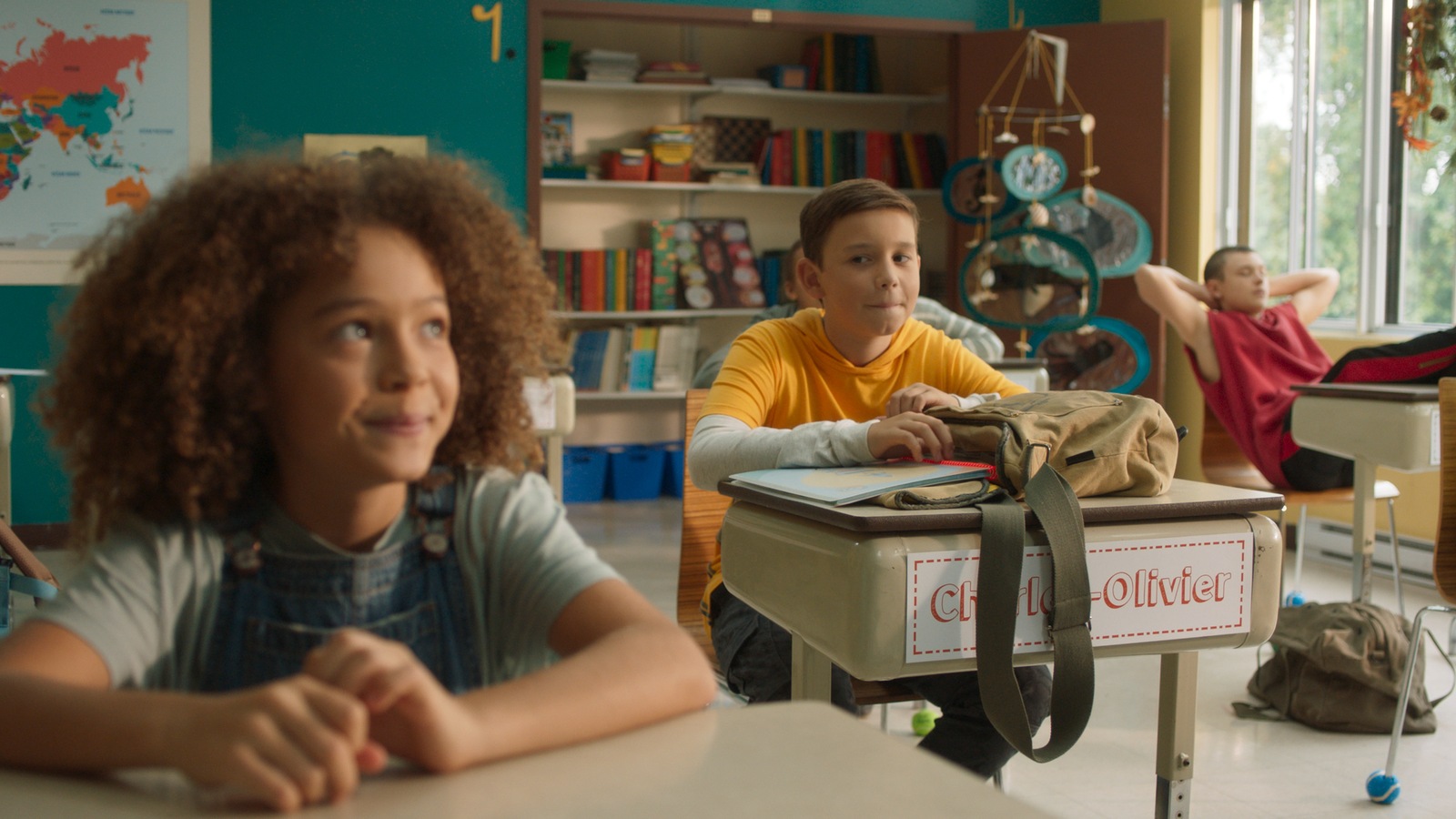 Deux personnages sont assis à leur pupitres dans une salle de classe. Lolo regarde Justine du coin de l'œil. Deux personnages sont assis à leur pupitres dans une salle de classe. Lolo regarde Justine du coin de l'œil.