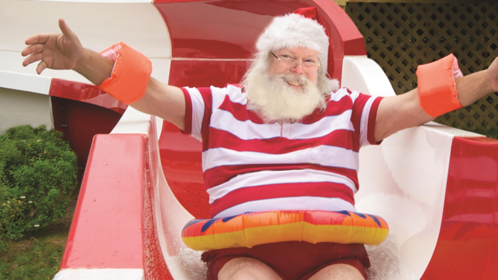 Le père Noël glisse dans une glissade d'eau, une bouée autour du ventre. Le père Noël glisse dans une glissade d'eau, une bouée autour du ventre.