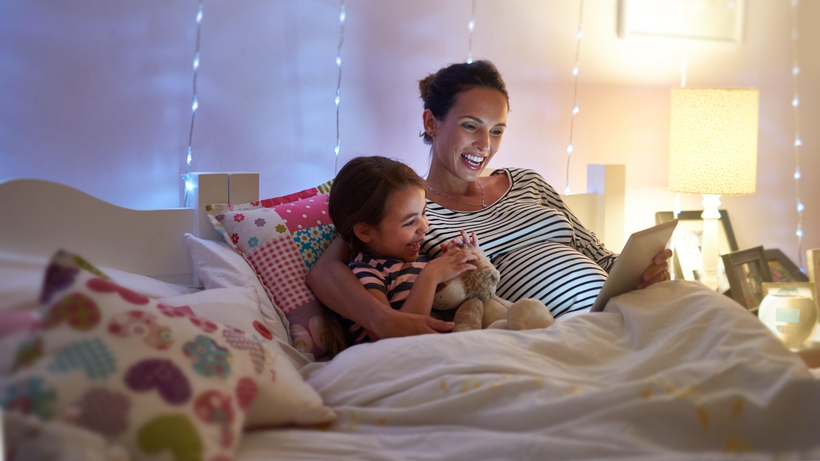 Une femme enceinte lit une histoire à sa fille dans son lit. Une femme enceinte lit une histoire à sa fille dans son lit.
