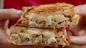 Une personne qui tient un sandwich au thon dans ses mains.