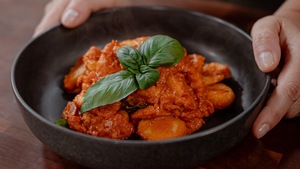 Des bouchées de tofu recouvertes de sauce rosée dans un bol.