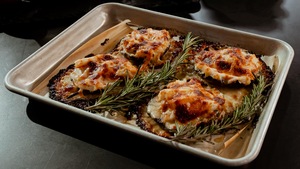 Quatre champignons portobellos sur une plaque farcis de crabe et gratinés.