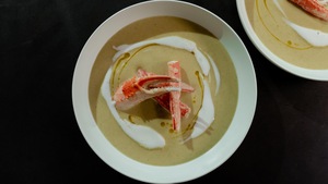 Deux bols de crème de courgettes et crabe avec des pinces de crabe en guise de décoration.