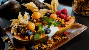 Une papaye garnie de yogourt, de granola et de fruits.