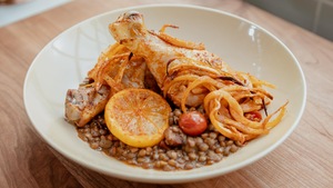 Des pilons de poulet sur un nid de lentilles vertes tomatées.