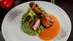 Du poulet rôti dans une assiette avec une sauce au poivron rouge et une purée de brocoli.