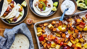 Tacos végé à la plaque dans deux assiettes et légumes sur une plaque.