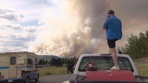 Un homme observe au loin les ravages causés par le feu