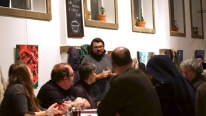 L'écrivain discute dans un café devant quelques personnes.