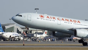 Un avion d'Air Canada passe devant un autre d'Air Transat à l'aéroport Montréal-Trudeau.