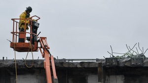 Un ouvrier dans une nacelle travaille sur une vieille poutre de l'ancien pont Champlain.