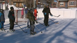 Antoine Bouchard et plusieurs jeunes sur la patinoire devant un but de hockey.
