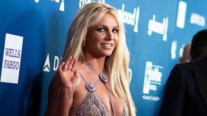 La chanteuse Britney Spears salue la caméra de la main lors d'un événement médiatique.