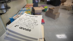 Des cahiers scolaires devant des livres et des boîtes dans une école.