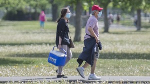 Un homme et une femme portant un masque marchent dans un parc.