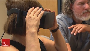 Une femme essaie des lunettes de réalité virtuelle à côté de Frédéric Banville.