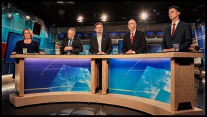 Une femme et quatre hommes devant une table, sur un plateau de télévision 