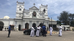 Des gens marchent devant une église blanche.