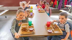 Des enfants assis à une table qui mangent leur repas.