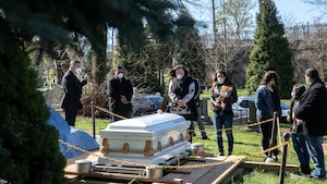 Des gens portant des masques assistent à un enterrement à Brooklyn, aux États-Unis.