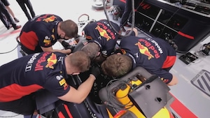 Quatre personnes penchées sur une voiture de F1 pour son inspection.