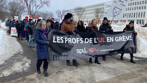 Des professeurs manifestent sur le campus de l'Université Laval. Ils portent une banderole et des pancartes. 
