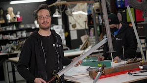 Ian Forand dans l'atelier avec une épée en mousse.
