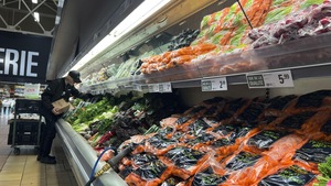 Un employé place des légumes dans un réfigérateur.