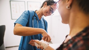 Une infirmière applique un bandage autour du poignet et de la main d'une patiente.