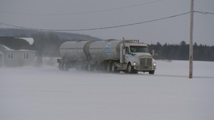 Un camion-citerne transportant du lait sur une route de campagne en hiver.
